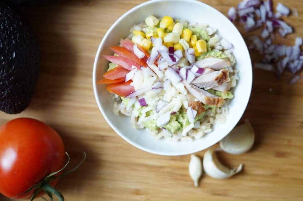 guacamole bowl - a gluten free recipe with corn, red onions, tomatoes, chicken, brown rice, and cheese
