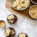 3 bowls of Chocolate Pudding with Peanut Butter topped with bananas and chopped peanuts