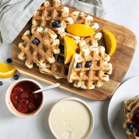 platter of orange poppyseed protein waffles with two sauce options : berry and vanilla custard
