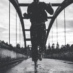 black-and-white-photo-of-woman-running-on-bridge-in-the-rain