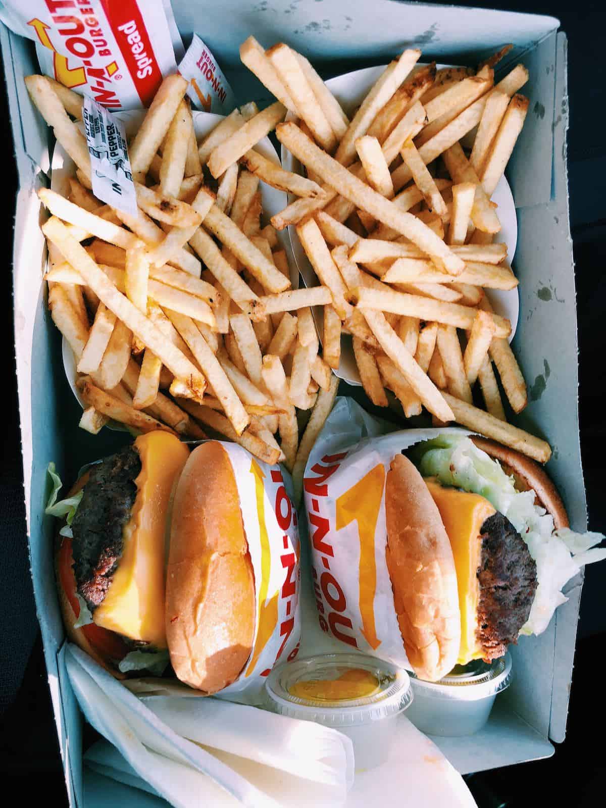 A flay lay photo of two bags of fries and two cheeseburgers.