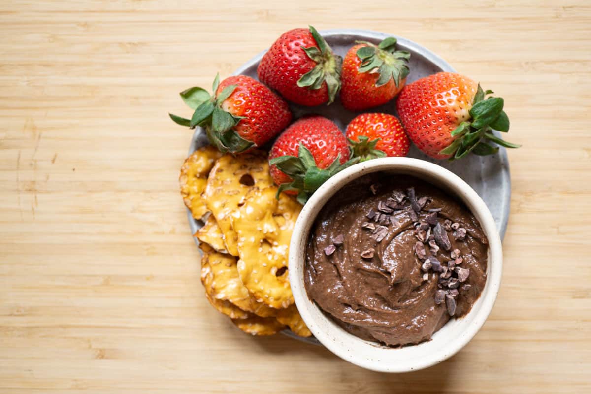 brownie batter hummus in a bowl with pretzel crackers and strawberries