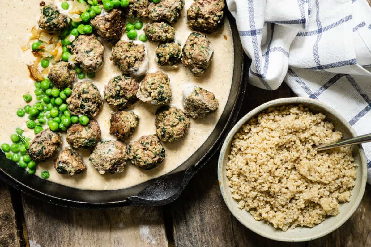 Swedish meatballs in sauce in pan beside a bowl of brown rice