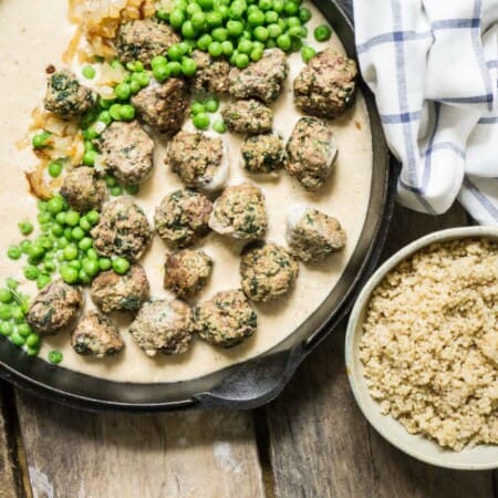 swedish meatballs in a cast iron pan with a bowl of rice and peas