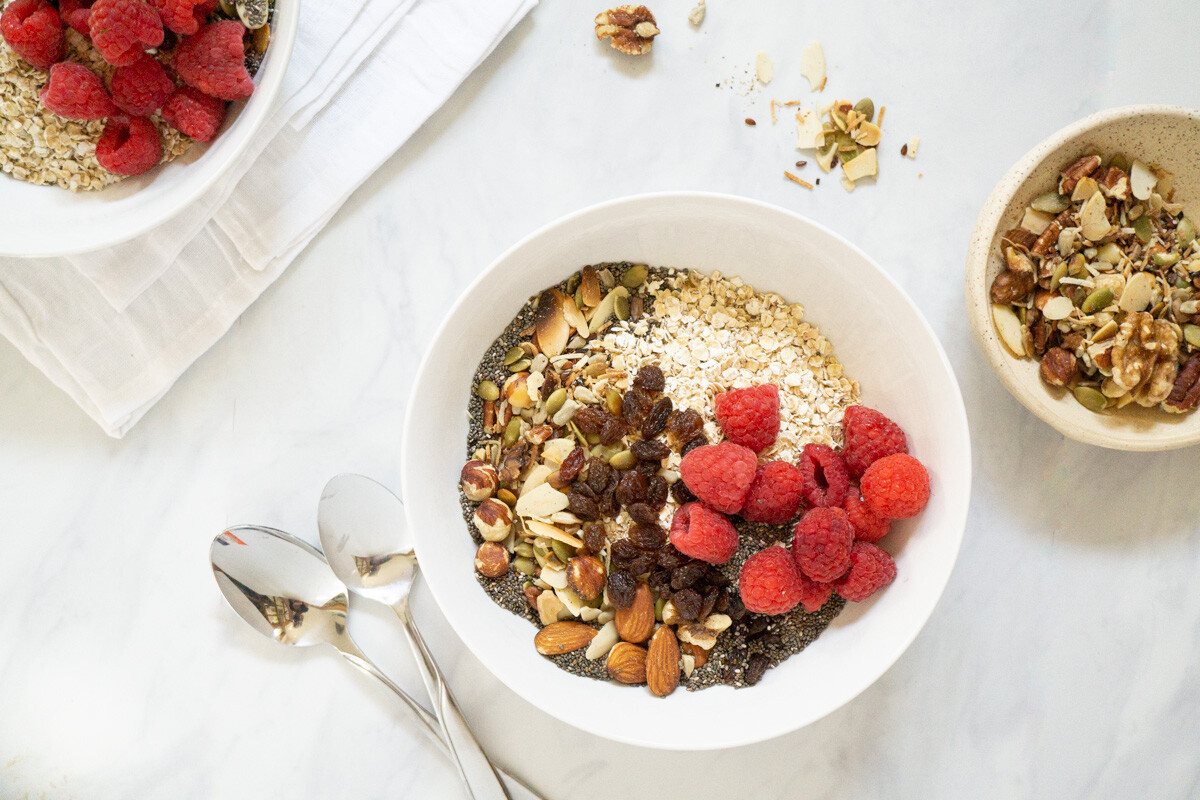 A couple bowls of homemade museli topped with fresh raspberries.