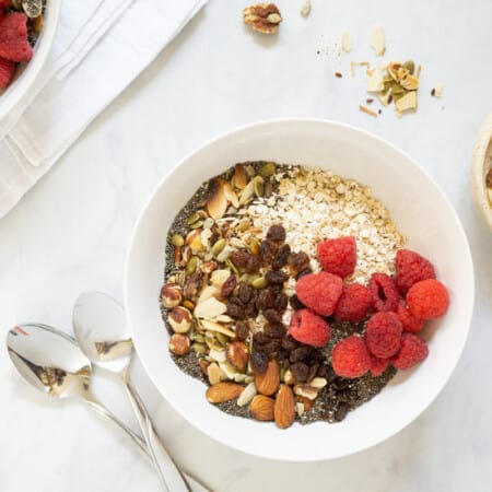 A couple bowls of homemade museli topped with fresh raspberries.