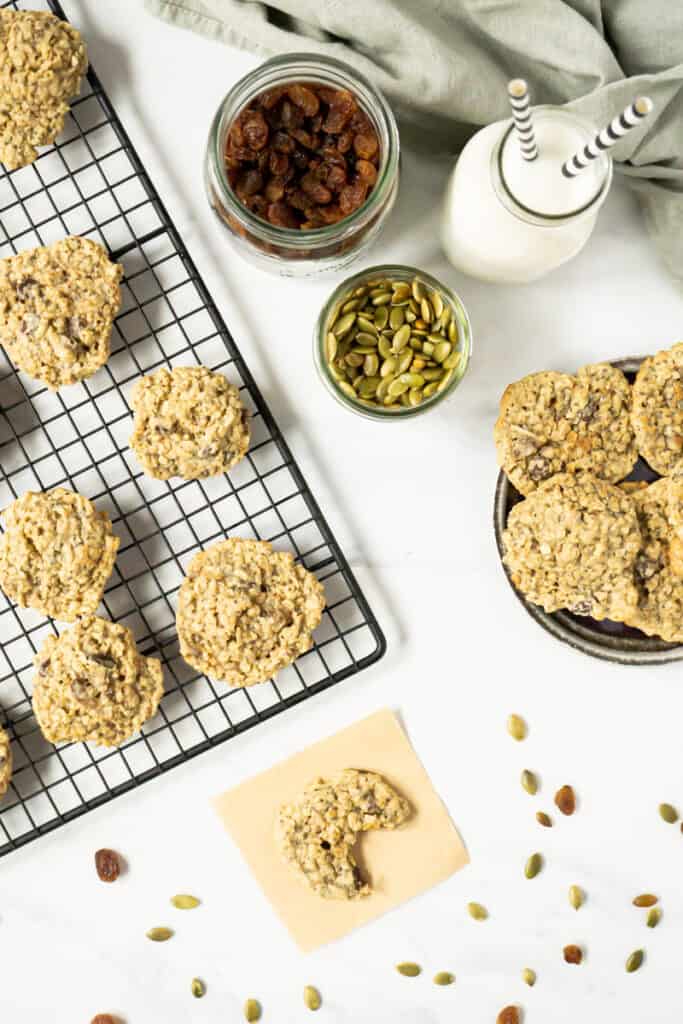 Birds eye view of trail mix cookies on a cooling rack and on a plate with a jug of milk.