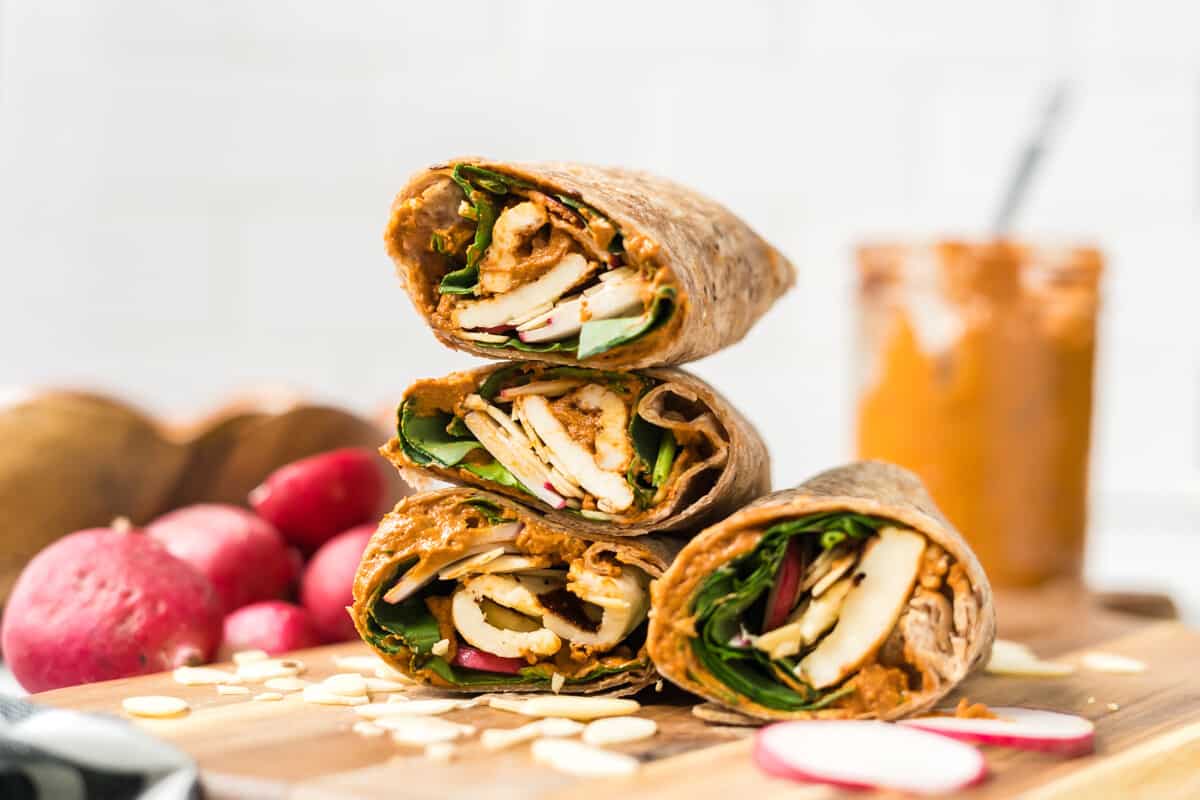 a side view of halloumi wraps with spinach, radishes, and romesco sauce