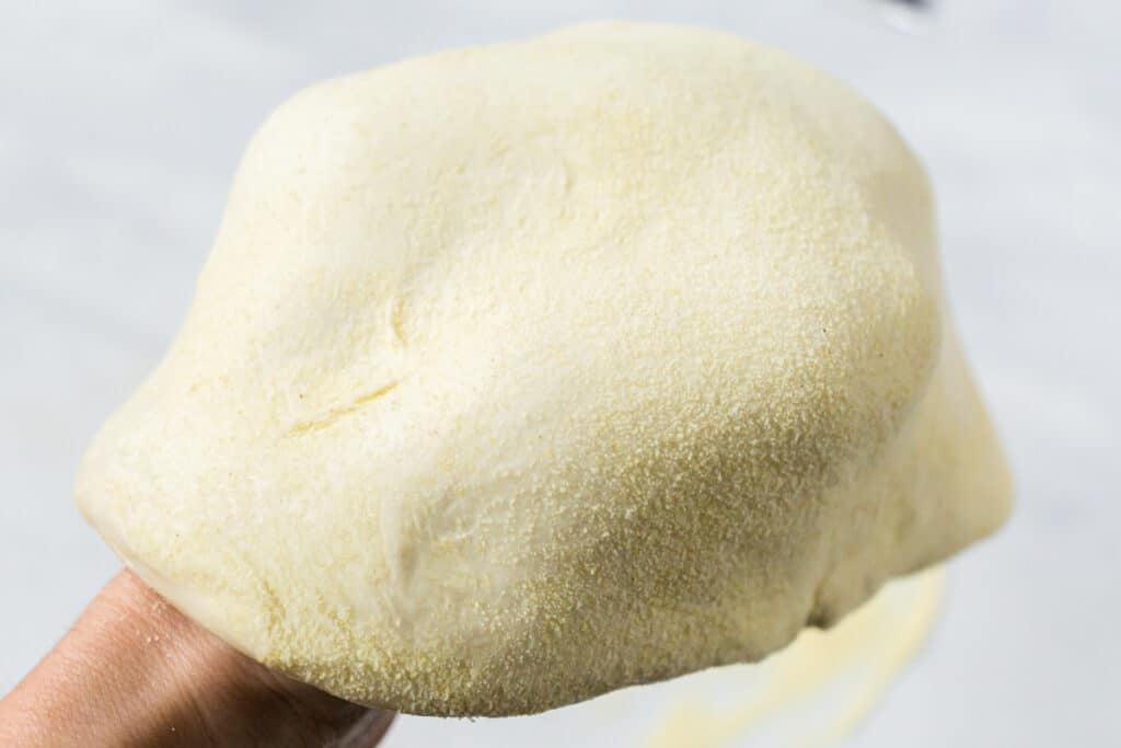 Picture of stretching sourdough pizza dough with two hands underneath the dough.