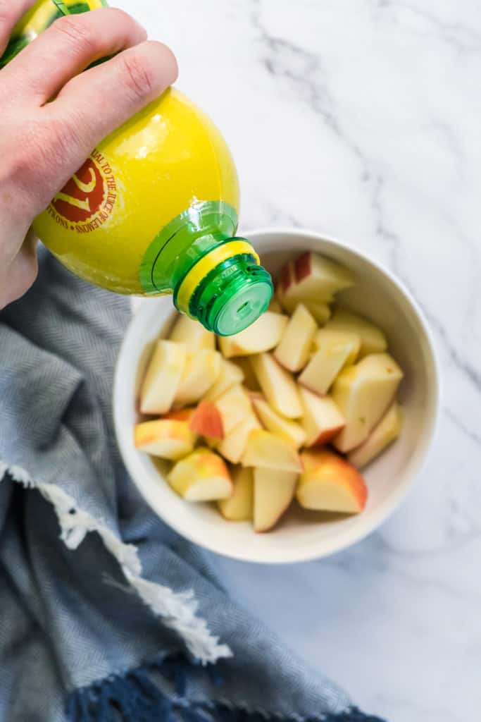 The first step in making this apple arugula salad is to dip the apple slices in lemon juice to prevent them from browning. 