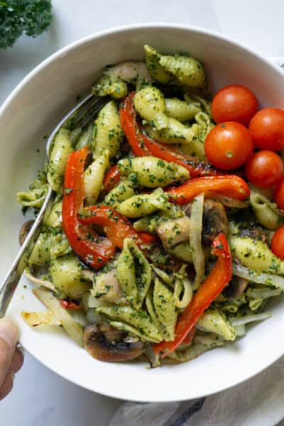 A bowl of penne dressed with a vegan walnut pesto and topped with veggies.