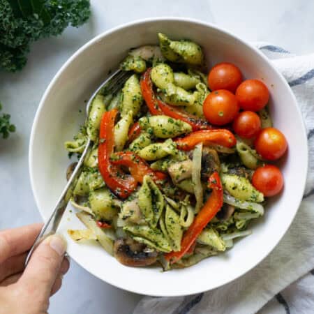 A bowl of penne dressed with a vegan walnut pesto and topped with veggies.