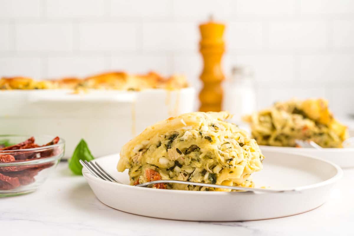 a slice of white chicken lasagna in front of the pan of lasagna