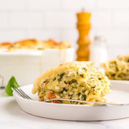 a slice of white chicken lasagna in front of the pan of lasagna